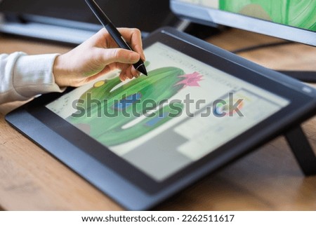 close up of a girls hand drawing on a digital tablet. drawing on a digital drawing board. Graphic designer working from home Royalty-Free Stock Photo #2262511617