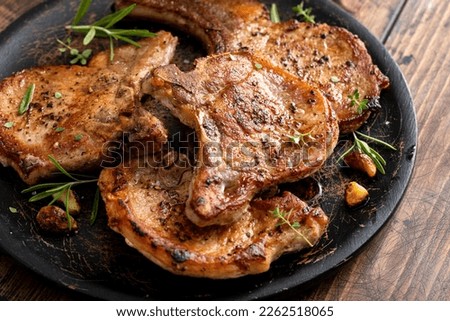 Pork chops grilled or seared with garlic and herbs bone in on a serving plate Royalty-Free Stock Photo #2262518065