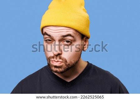 A man with a doubtful expression, his facial features twisted into a funny grimace, captured in a studio shot while looking at the camera. Anxiously Enchanted A Studio Shot of a Man's Fascination Royalty-Free Stock Photo #2262525065