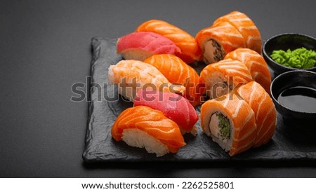 Set of traditional Japanese sushi and rolls angle view with soy sauce and wasabi on dark black rustic slate. Sushi with salmon, tuna, shrimp