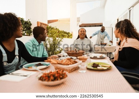 Happy african family eating lunch together at home terrace outdoor - Focus on senior woman face