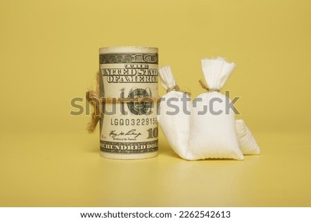 A picture roll of fake money and money bag on yellow background. Time value of money concept.