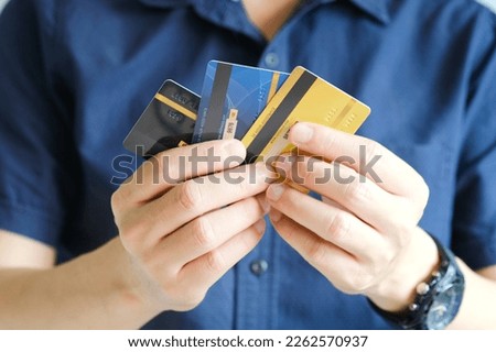 Man holding several credit cards and he is choosing a credit card to pay and spend Payment for goods via credit card. Finance and banking concept. Royalty-Free Stock Photo #2262570937