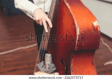 Contrabass cellist player in headphones during rehearsal, recording sound for new album song at studio, cello violoncellist musician with microphone and musical band orchestra, music production