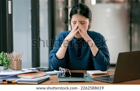 Asian women are stressed while working on laptop, Tired asian businesswoman with headache at office, feeling sick at work. Royalty-Free Stock Photo #2262588619