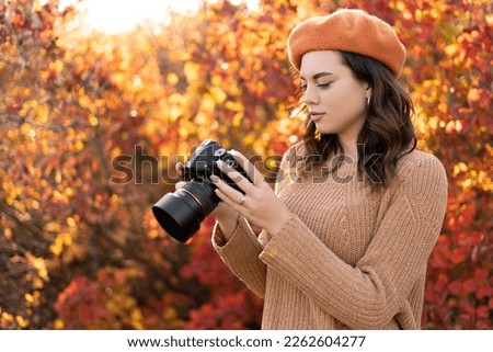 Young woman photographer holding camera taking pictures photos of autumn yellow forest park. Lady walking in fall park with yellow and orange foliage. Copy space