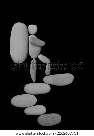one Hiker man climbing with big heavy backpack on mountain. isolated on black background. male sign, symbol made from many white pebbles, stones. peak of mountain.