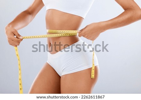 Weightloss, health and woman with measuring tape in a studio for her diet, exercise or wellness. Fitness, body and healthy slim female model checking the measurement of her waist by a gray background Royalty-Free Stock Photo #2262611867