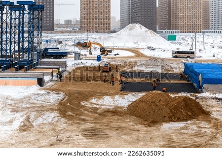 At the construction site, workers dig the ground with shovels