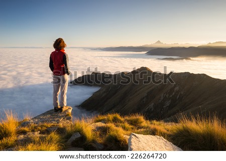 Female hiker reaching her goal at the mountain top and looking at majestic panoramic view of the italian western Alps with M. Viso peak in the background. Wide angle view at sunset. Royalty-Free Stock Photo #226264720