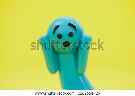 Surprised blue doll on yellow background