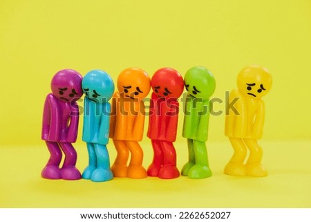 Sad looking colorful dolls on yellow background