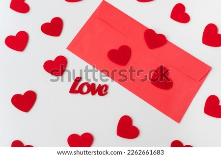 A love letter, the inscription of love on a red paper envelope on the background of small red hearts. Selective focus, noise. The concept of St. Valentine's Day