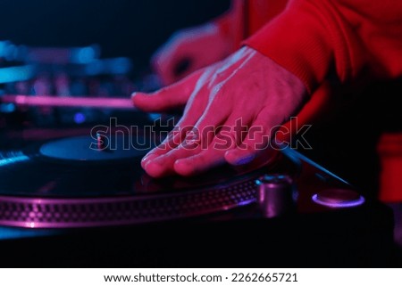Hip hop dj scratching vinyl records on turntable. Club disc jockey playing music on party. Hand of disk jokey on a record in close up photo Royalty-Free Stock Photo #2262665721