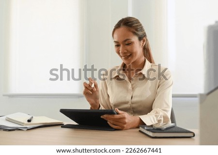Pleasant young female employee checking email or searching information online on digital tablet