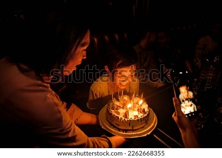 
cake with candles  birthday mom and son blow out the candles take pictures on the phone