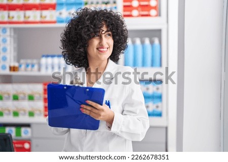 Young middle east woman pharmacist smiling confident writing on document at pharmacy