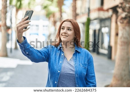 Young beautiful plus size woman smiling confident making selfie by the smartphone at street