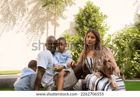 Mixed raced family sitting together with a dog Royalty-Free Stock Photo #2262706555