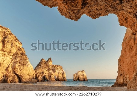 Algarve, Portugal - View of Alvor beach from inside a cave in the cliffs at sunset - Summer vacation concept