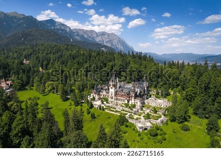 Aerial view of Peles Castle with Bucegi Mountains in background during a beautiful sunny day. Landmarks of Romania. Royalty-Free Stock Photo #2262715165