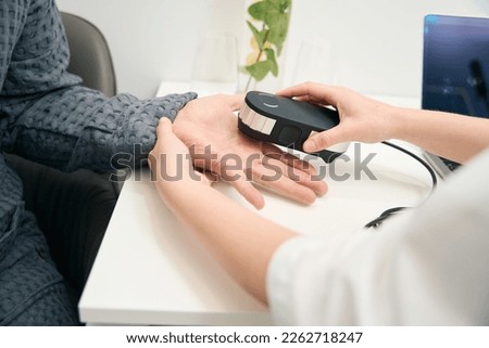 Picture of doctor hands with oligoscan is doing analysis in health center