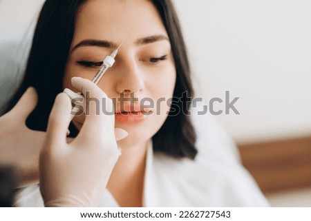 Portrait of young Caucasian woman getting botox cosmetic injection in forehead. Beautiful woman gets botox injection in her face. Royalty-Free Stock Photo #2262727543