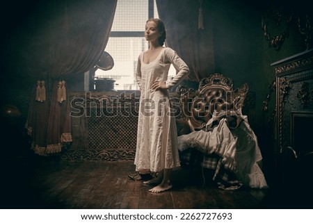 Scottish clothing of the 18th century. A medieval noble woman is getting dressed in a Scottish costume and shoes of the 18th century in a room with classic vintage interior.  Royalty-Free Stock Photo #2262727693