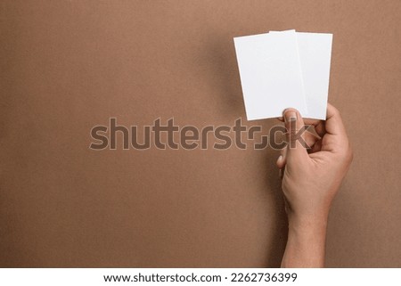 Man holding sheets of paper on brown background, closeup. Mockup for design