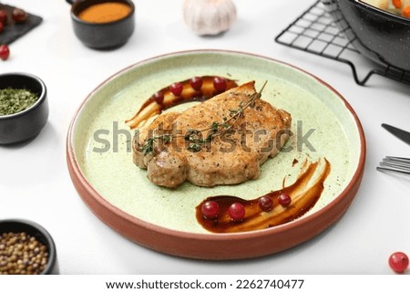 Beautiful composition with plate of delicious meat on white table in studio. Food stylist