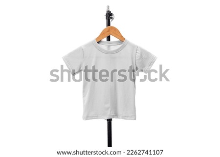 Small Styles, Big Smiles: Mockup of Kids T-Shirt on Rustic Wooden Hanger Hanging from Industrial Black Steel Pipe Royalty-Free Stock Photo #2262741107