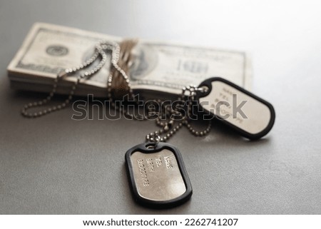 The soldier's military tokens are on dollar bills. Concept: cost of living soldier, military pensions, soldiers of fortune and mercenary Royalty-Free Stock Photo #2262741207