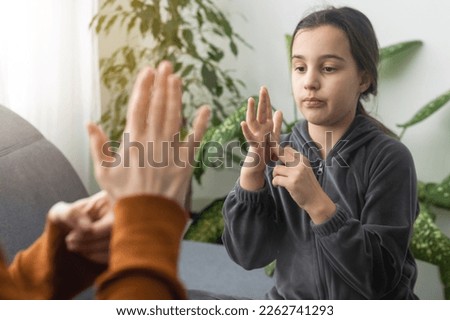 Small Caucasian teen girl child do articulation exercises with caring mother or teacher at home. Little kid pronounce sounds speak talk with tutor or coach, engaged in voice pronunciation together Royalty-Free Stock Photo #2262741293