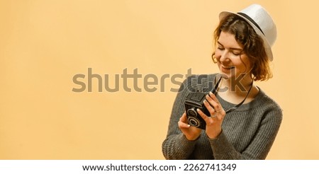 Stylish woman photographer with retro camera on the yellow wall background. Image with copy space.