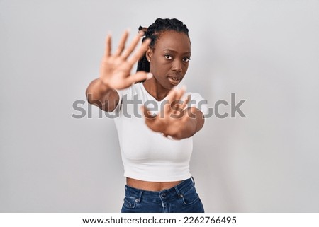Beautiful black woman standing over isolated background doing frame using hands palms and fingers, camera perspective 