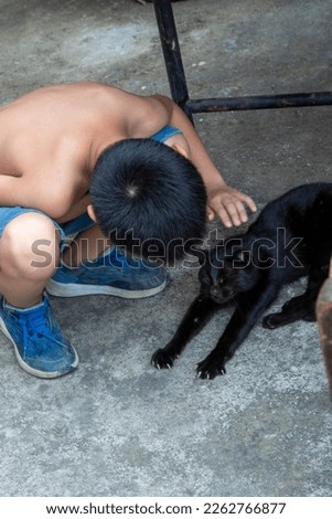 Little boy petting black cat at home