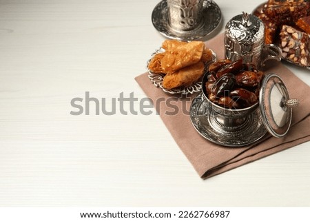 Tea, date fruits, Turkish delight and baklava dessert served in vintage tea set on white wooden table, space for text