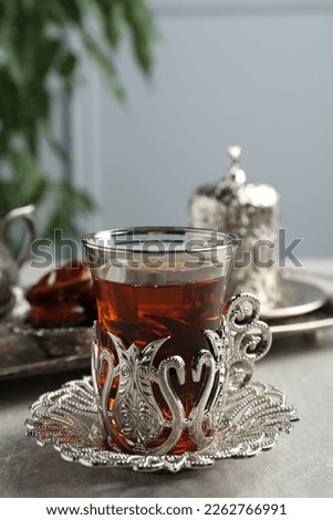 Tea and date fruits served in vintage tea set on grey table, space for text