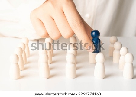 Hands take blue wooden figure out of crowd. Concept of rare disease, LGBTQ, virus epidemic, human resource, staff recruitment, talent, leadership and unique. Royalty-Free Stock Photo #2262774163