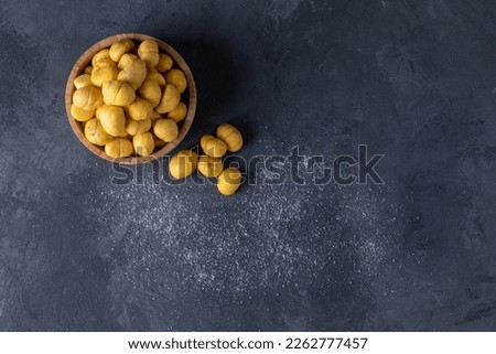 peeled chestnuts in a wooden bowl and some of the chestnuts scattered around Royalty-Free Stock Photo #2262777457