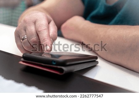 An elderly woman uses a phone, scrolls through the news feed in her smartphone. Hands of an elderly woman with a smartphone swipe finger on the screen sensor. Make an online order in online shopping