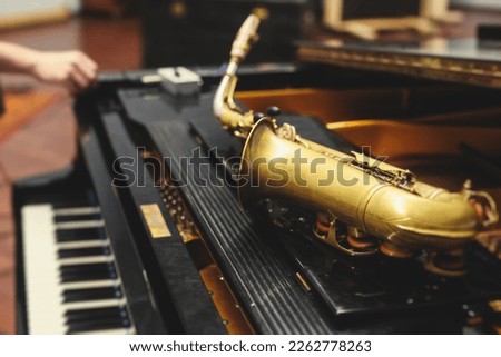 View of a saxophone player in headphones during rehearsal, recording sound for new album song at studio, saxophonist musician in front of microphone with a musical band orchestra, music production
