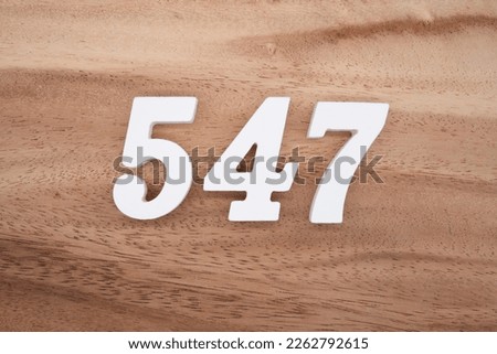 White number 547 on a brown and light brown wooden background.
