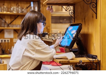 Female restaurant worker using computer terminal while serving customers Royalty-Free Stock Photo #2262796071