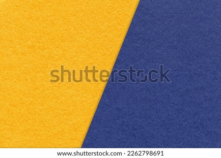 Texture of craft yellow and navy blue paper background, half two colors, macro. Structure of vintage dense kraft golden cardboard. Felt denim backdrop closeup.