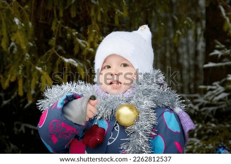 Young small girl walking and having photo shoot in park or forest full of snow in a cold winter day. Female child having fun in winter day
