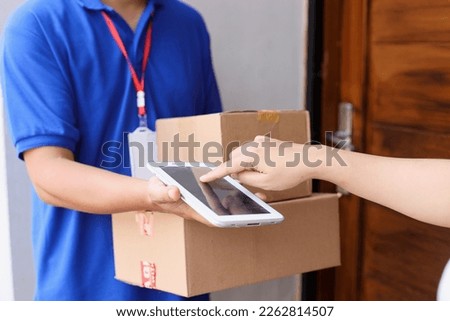 Cropped shot of customer sign on tablet while receiving package from deliveryman