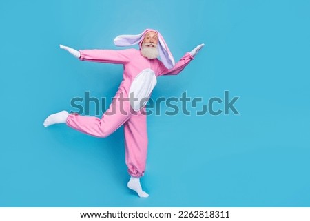 Full size photo of funky optimistic glad elderly pensioner wear pink bunny costume flying dancing isolated on blue color background