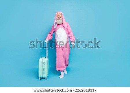 Full length photo of funky cool pensioner guy dressed bunny kigurumi walking airport check in empty space isolated blue color background