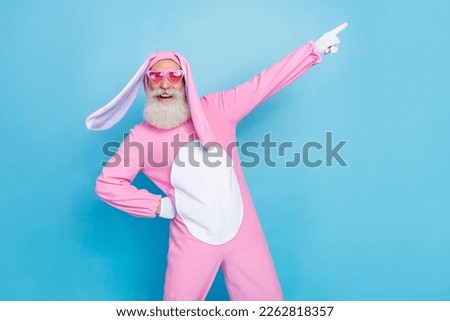 Photo of funky positive man dressed pink rabbit costume sunglass directing empty space hand on waist isolated on blue color background
